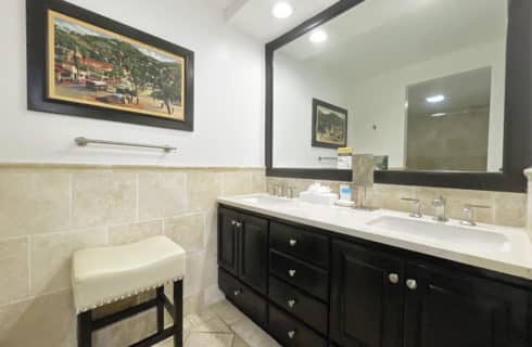 Bathroom with light tan tile on walls, floor, and tub with dark wood vanity and granite countertop