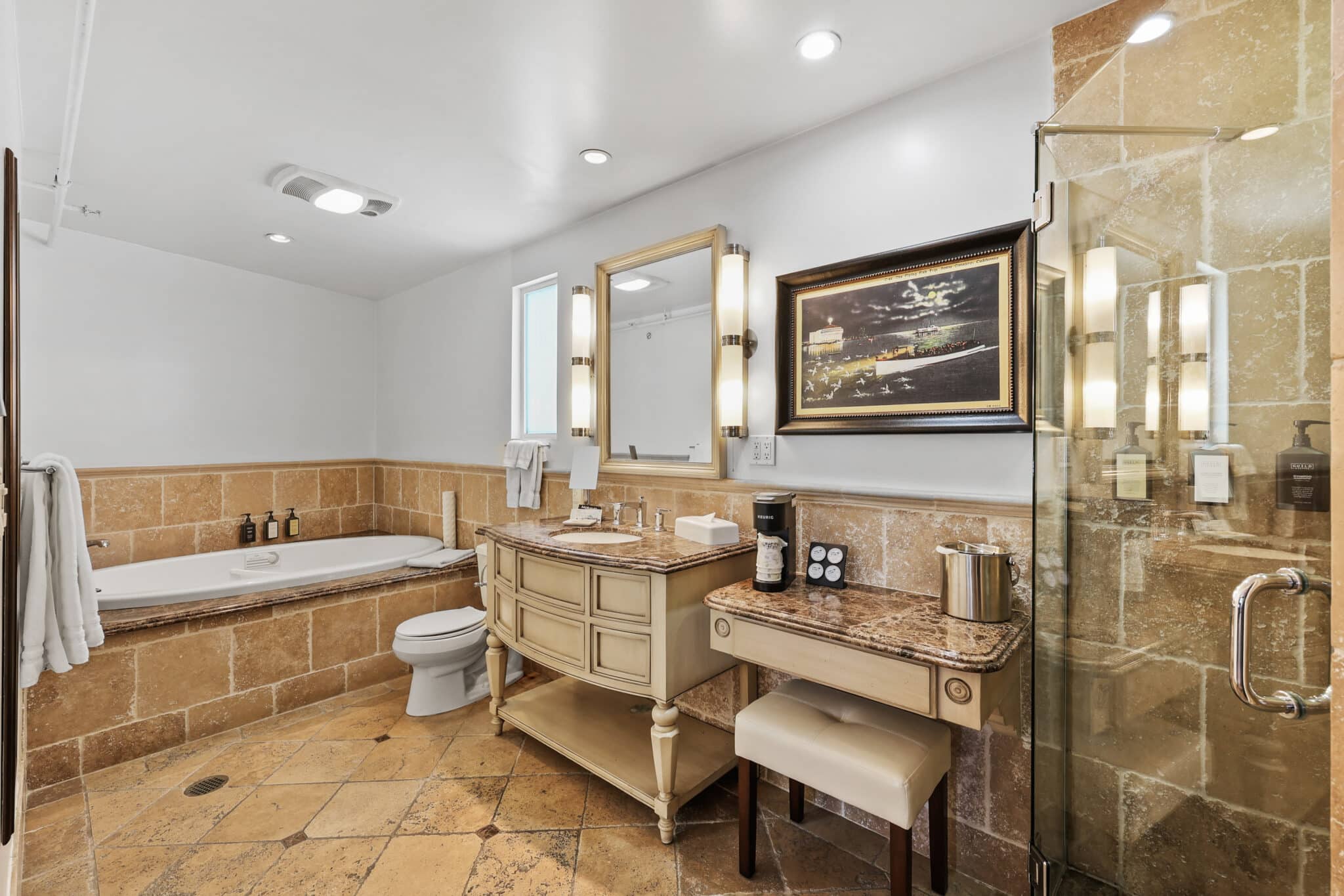 Vanity with toilet with tile foor and surround with vanity lights and white walls