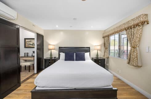 King size bed with side tables lamps and blue pillows and white walls.