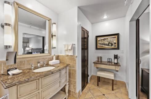 Sink and vanity with chair mirror with tile floor and surround with white walls