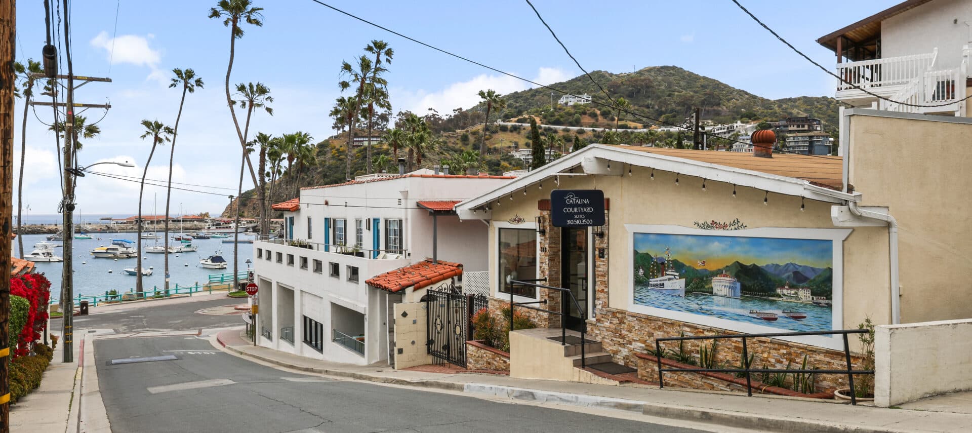 front of hotel from the street wtih Catalina Couryard in the background and ocean and palm tress in the back.