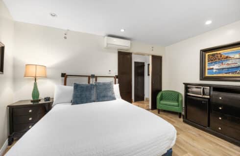 King size bed with blue pillows lamps and green chair