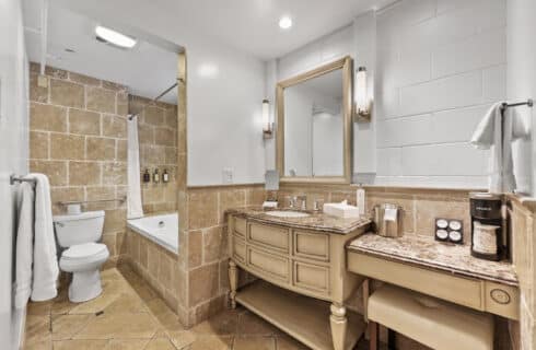 Vanity and tub with toilet, tiled surroundinds