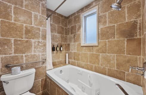 Toilet and Jetted tub with tile surround.