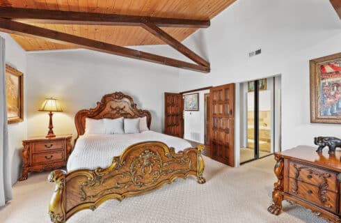 King sized bed with carpet white linens and wood furniture
