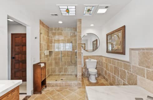 Penthouse main stand up shower with toilet. Tiled bath area