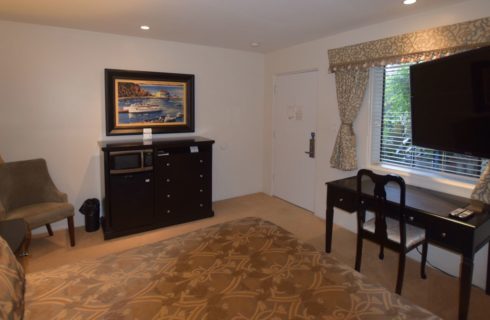 Bedroom with dark wood dresser, desk, and chair with an additional upholstered chair and lamp