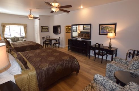 Very large room with two king beds, couch, table with chairs, desk with chair, two upholstered chairs, and larger dresser