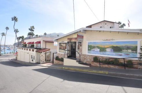 Outside view of property painted off white with white trim located near marina and hills
