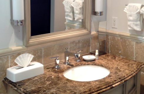 Bathroom vanity with dark and light brown granite counter top and mirror with cream-colored wooden frame